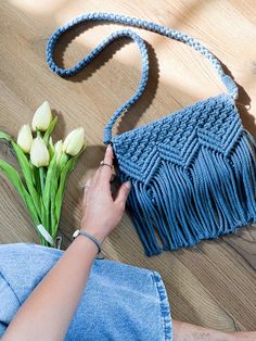 a woman is holding a blue purse next to some tulips on the floor