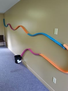 a room with a wall that has some colorful hoses on the side of it