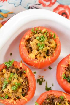 four stuffed red peppers on a white platter with parsley in the top half