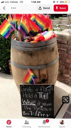 a wooden barrel filled with rainbow flags and a sign that says grab a flag hold in tight