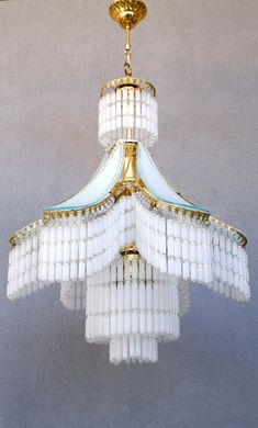 a chandelier hanging from the ceiling with white and gold trimmings on it