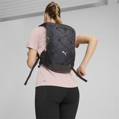 a woman with a pink shirt is carrying a black backpack