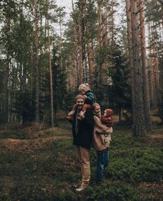 a man carrying two children in the woods