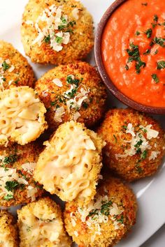 some food is on a white plate next to a small bowl of tomato sauce and garnished with parmesan cheese