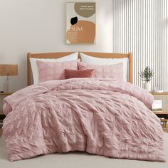 a bed with pink comforter and pillows in a room