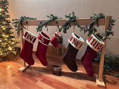 three stockings hanging from a wooden rail in front of a christmas tree