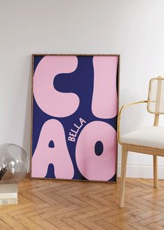 a pink and blue poster sitting on top of a wooden floor next to a chair