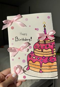 a hand holding up a birthday card with a cake on it and pink bows around the edges