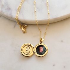 The Locket Necklace with Photo is a beautiful and sentimental piece of jewelry that is perfect for keeping your loved ones close to your heart. This personalized necklace features a round locket pendant that opens up to reveal a space for your favorite photo. The locket is 18K gold plated, which gives it a luxurious and timeless look. The necklace itself is also 18K gold plated and adjustable to fit any neck size comfortably. It has a secure clasp that ensures the locket stays in place, so you c Gold Spiritual Personalized Locket Necklace, Personalized Locket Necklace For Mother's Day Memorial, Personalized Spiritual Necklaces For Keepsake, Round Birthstone Locket Necklace For Anniversary, Anniversary Birthstone Locket Necklace, Delicate Personalized Medallion Jewelry, Birth Flower Pendant Jewelry For Memorial, Dainty Locket Jewelry For Mother's Day, Gold Pendant Locket Necklace With Birthstone