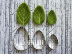 three leaf shaped spoons sitting next to each other on top of a tablecloth