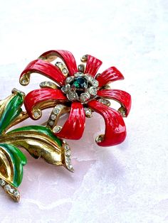 Beautiful, Elegant Unsigned Enamel flower brooch This brooch is approx 3 1/8 X 2 1/2 nches, quite a statement piece! The brooch features Gorgeous enamel red flowers with an emerald colored center stone, surrounded by clear chatons. Petals are accented on the ends also with clear chatons. Enamel is in great condition as is the gold finish on the back. The back finish however is in great condition for its age. I haven't been able to find a patent for this piece but I believe this to be from around Vintage Enamel Flower Brooches, Vintage Enamel Brooches For Anniversary, Vintage Flower Enamel Pin For Collectors, Vintage Flower Enamel Pin Collectible, Vintage Enamel Flower Brooch, Vintage Red Enamel Brooches, Red Enamel Vintage Brooch, Vintage Flower Enamel Pin, Vintage Bakelite