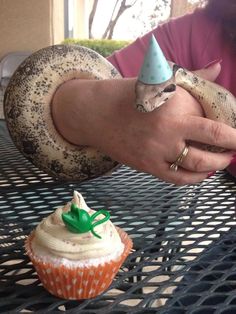 a person holding a cupcake with a snake on top