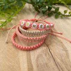 three bracelets with words on them sitting on a wooden surface