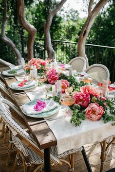 the table is set with flowers and plates on it, along with candles and place settings