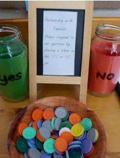 a wooden bowl filled with lots of buttons next to a chalkboard and some jars