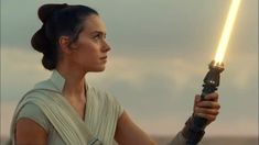 a woman holding a light saber in her right hand and looking off into the distance