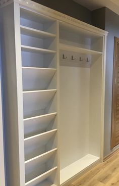 an empty room with white shelves and wooden doors on the wall, in front of a wood floor