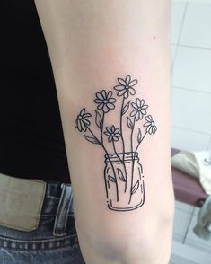 a woman's arm with flowers in a vase tattoo