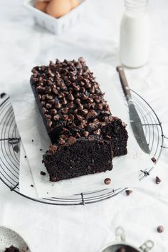 a chocolate cake sitting on top of a cooling rack next to a glass of milk