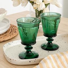 two green glasses sitting on top of a tray