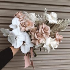 a bouquet of flowers is being held up by someone's hand in front of a garage door