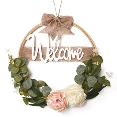 a welcome sign hanging on a wall with flowers