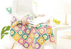 a woman sitting in a chair with a crocheted blanket on top of it