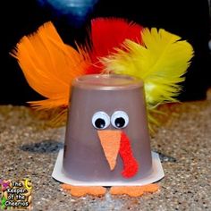 a plastic turkey bell with feathers on it's head sitting on a counter top