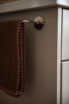 a towel hanging on the side of a refrigerator door with a metal hook in it