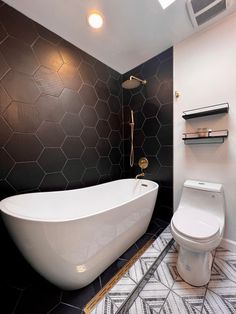 a white bath tub sitting next to a toilet in a bathroom under a skylight