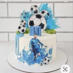 a birthday cake with a soccer player on the top and blue paint splatters around it