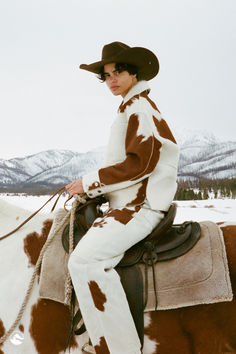 Model in a remote snowy location wearing a matching cowhide jacket and pant resort wear set and a cowboy hat, riding horseback on a horse that has a similar markings as the cowhide outfit Winter Cowboy, Holiday Party Attire, Ski Fashion, Skiing Outfit, Trendy Fall, Casual Fall Outfits, Fashion Photoshoot, Colorful Hoodies, Fall Outfit