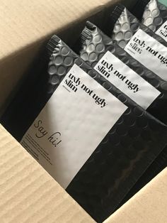 five packages of condoms sitting on top of a cardboard box with black and white labels