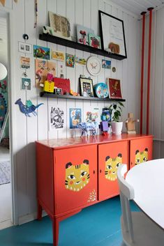 an orange cabinet with pictures on the top and shelves above it in a white room