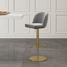 a grey and gold bar stool in front of a table with a plate on it