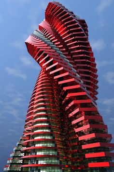 a very tall red building with many windows on it's side and the sky in the background