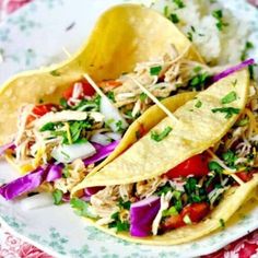 three tacos on a plate with rice and garnish