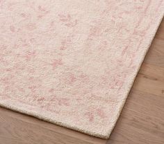 an area rug with pink and white designs on the top, sitting on a wooden floor