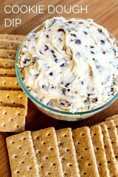 cookie dough dip in a glass bowl surrounded by crackers on a wooden table with text overlay