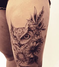 an owl and flowers tattoo on the thigh is shown in black and white, while it appears to be part of a woman's leg