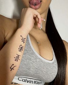 a woman sticking her tongue out with writing on her left arm and right hand in front of her face