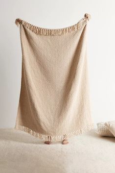 a beige blanket with tassels hanging from it's sides on a bed