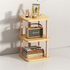 a wooden shelf with books and an old radio on it, next to a white wall