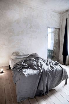 an unmade bed sitting on top of a wooden floor