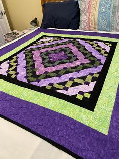 a bed with a purple and green quilt on it