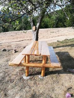 a wooden picnic table sitting under a tree