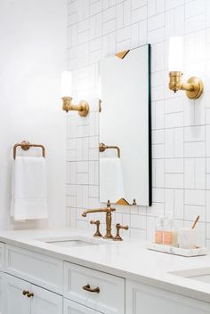 a bathroom with two sinks and gold faucets on the counter top next to a mirror