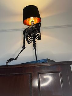 a lamp that is on top of a wooden cabinet with a skeleton attached to it