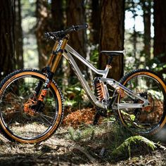 a bike is parked in the woods near some trees and grass with orange rims