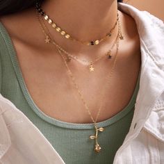 a close up of a woman wearing a necklace with stars and bells hanging from it